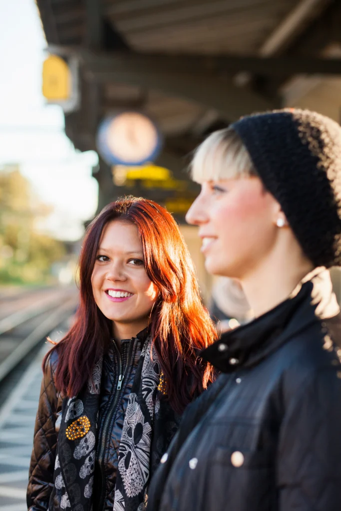 portrait of red-haired woman with happy friend at railway station